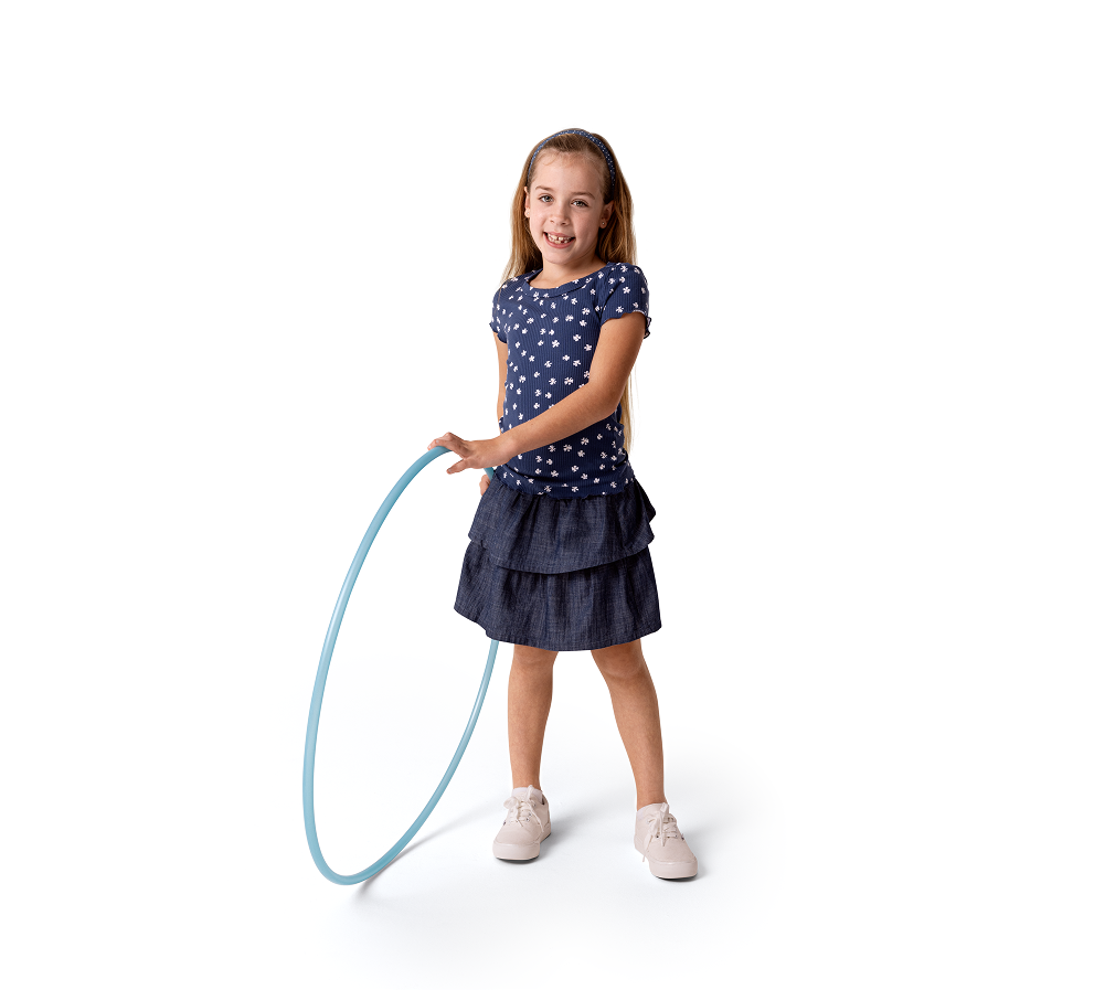 A young girl standing and holding a hula hoop
