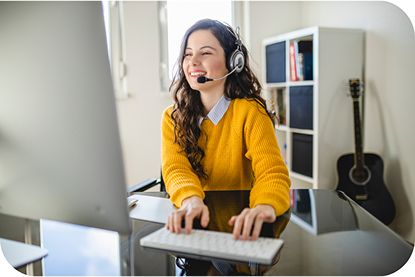 A woman wearing a headset as she types on her computer